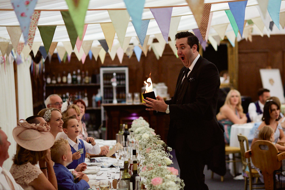 Funny wedding photo of magician Alexander James setting fire to his wallet at Broyle Place