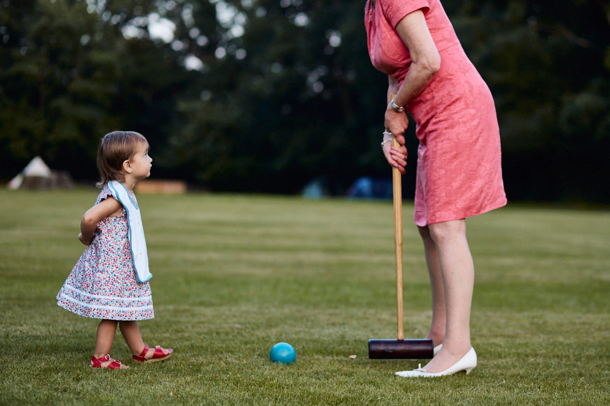 Funny wedding photo a girl playing croquet with a guest