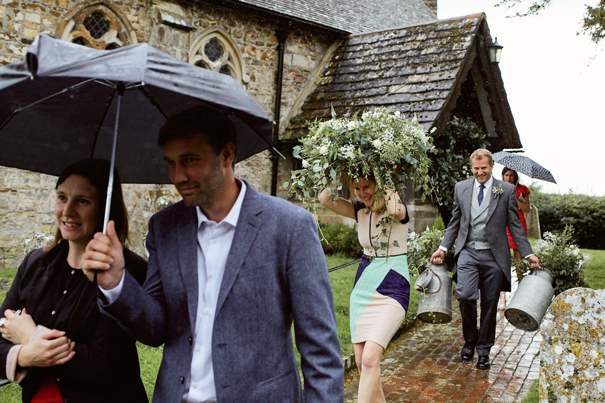 Funny wedding photo of a wedding guest sheltering from rain under a plant