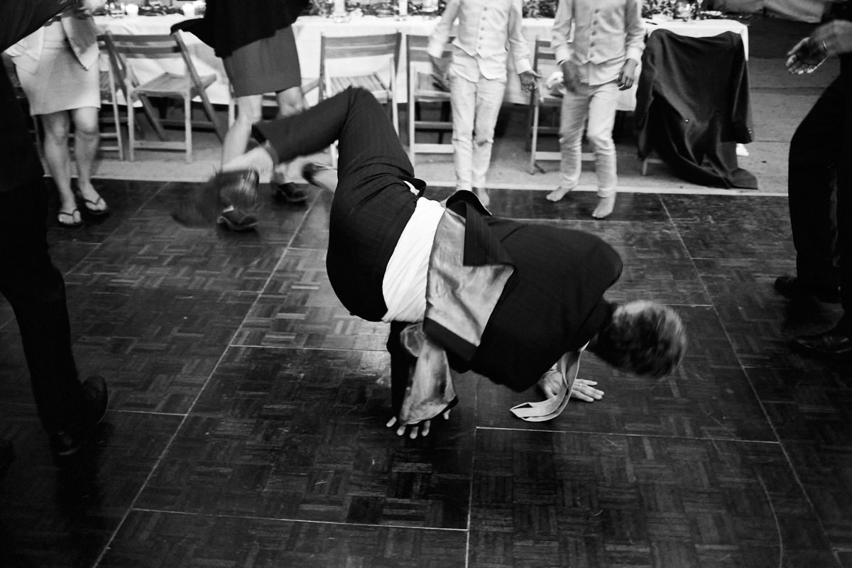 Funny wedding photo of a man in a suit breakdancing