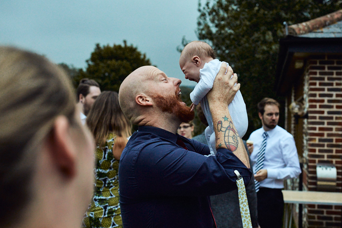 Funny wedding photo of a father pulling faces at his baby