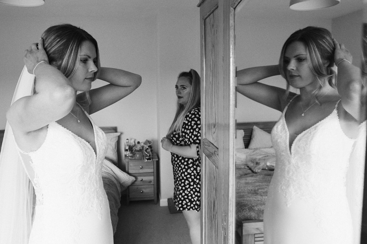 Bride adjusts hair in mirror before wedding