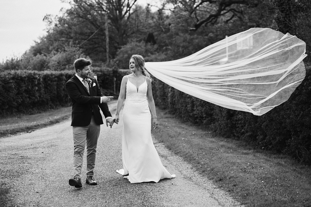 Groom points at bride's flyaway veil at Great Barn wedding