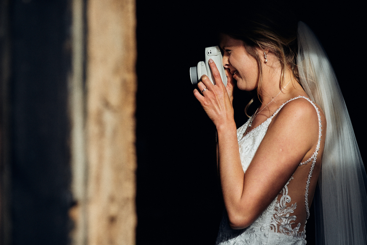 Bride takes a photo at Great Barn wedding in Kent