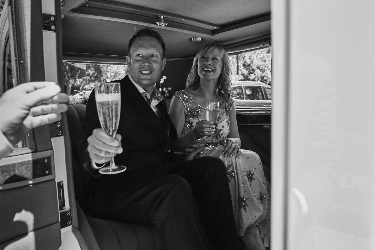Couple drink champagne in wedding car at Horsham Register Office in Sussex