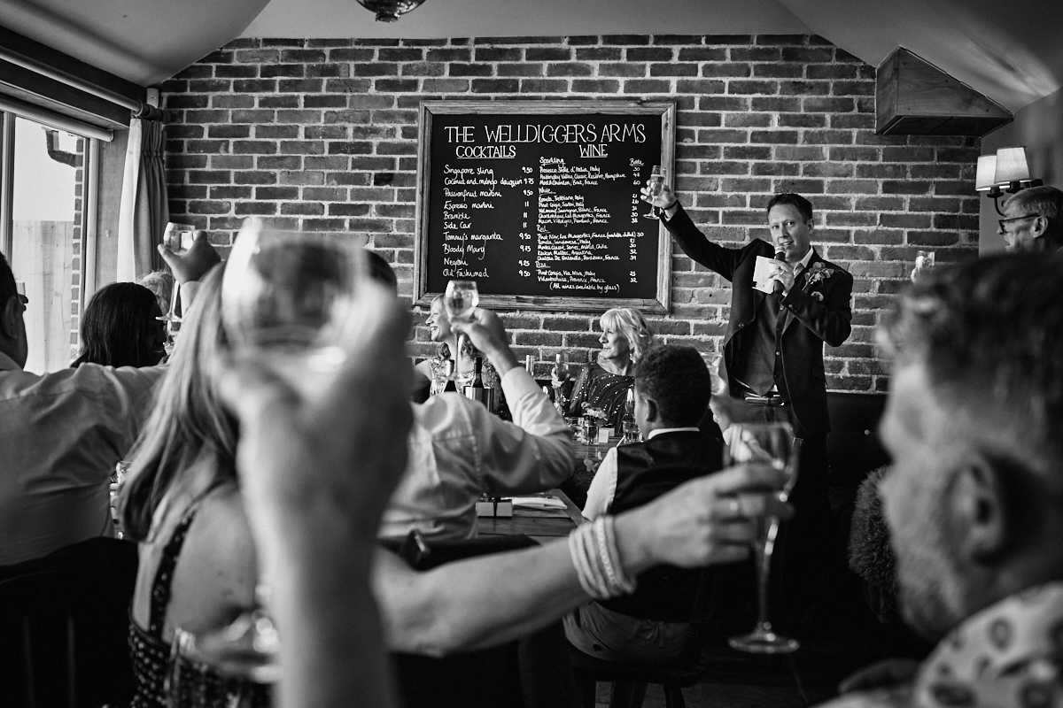 Groom welcomes guests at Welldiggers arms pub wedding in Petworth, Sussex