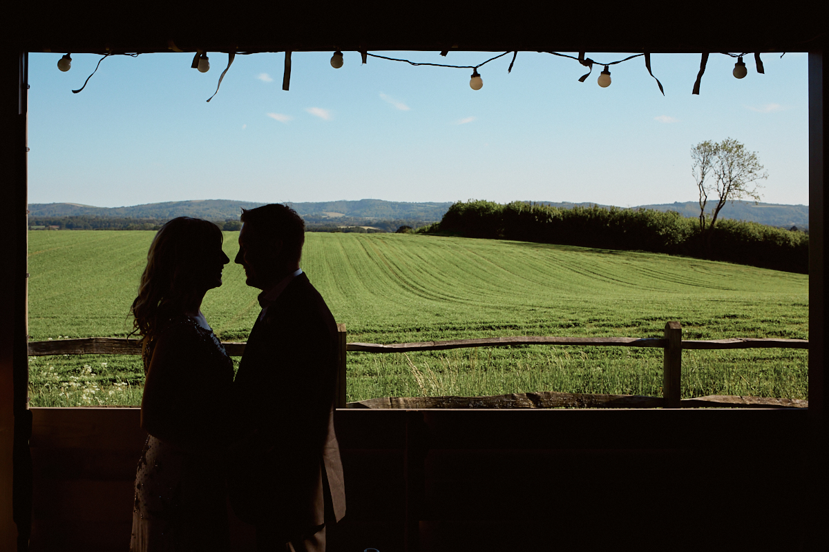 Silhouette of bride and groom in front of South Downs at Welldiggers arms pub wedding in Petworth, Sussex