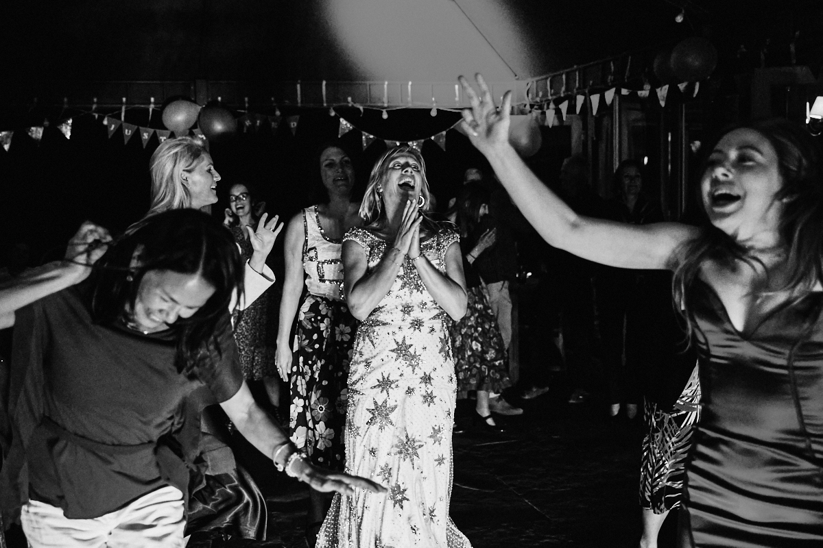 Black and white image of bride and guests dancing at Welldiggers arms pub wedding in Petworth, Sussex